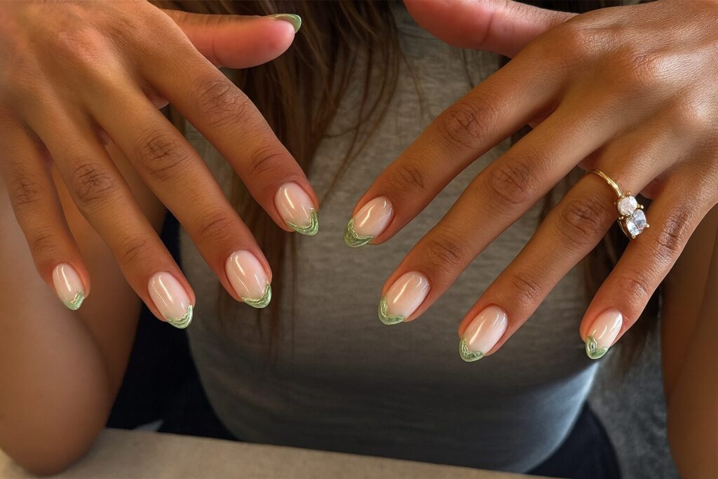 Green chrome French tip nails over a soft pink base with marzipan-inspired texture