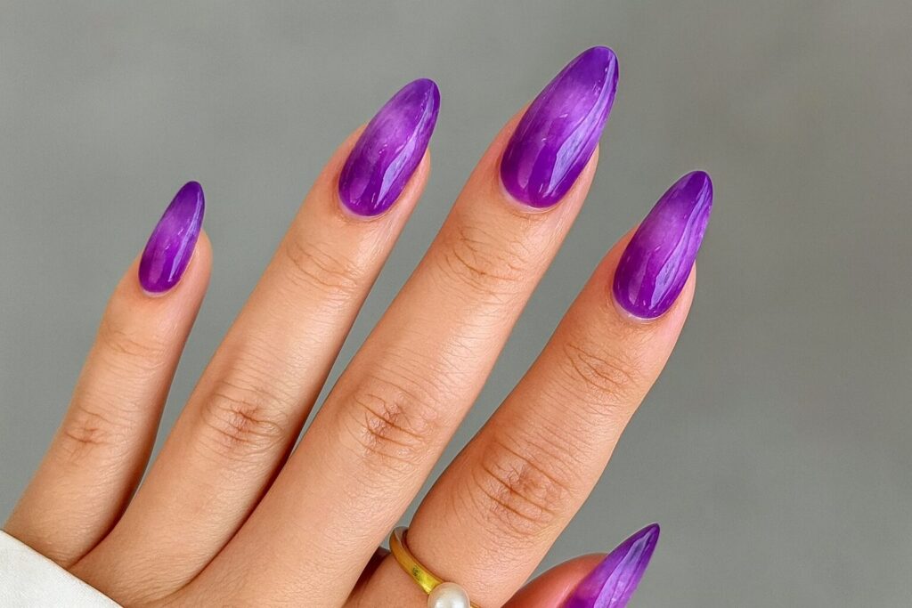 Swirly jelly nails with glossy amethyst-inspired purple tie-dye design.