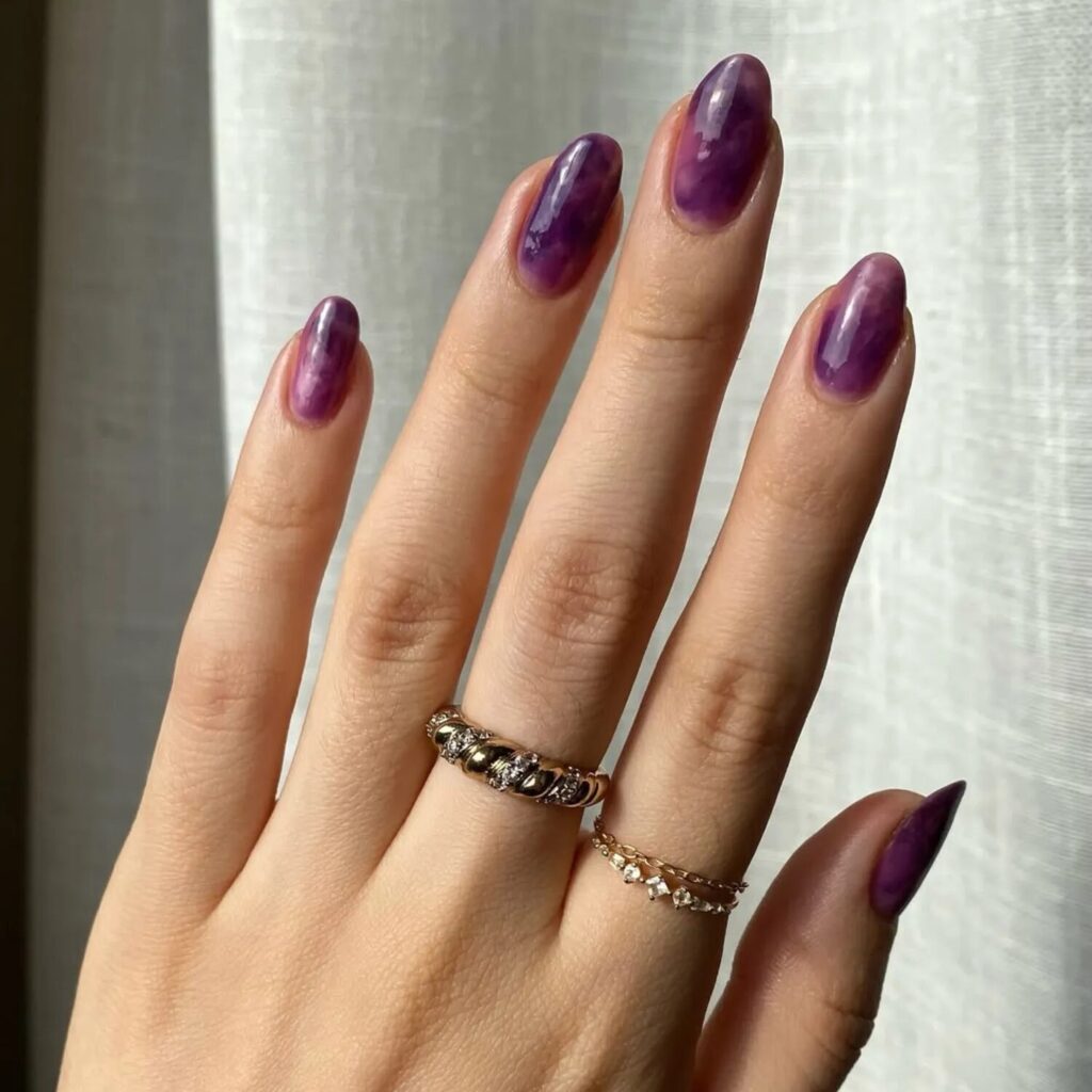 Ultra-realistic photo of nails with grape jelly polish in a soft lilac-purple tone, glossy sheer manicure for fall nail inspiration.