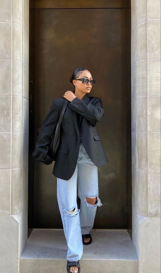 Stylish airport outfit featuring blue jeans, oversized black blazer, and crossbody bag