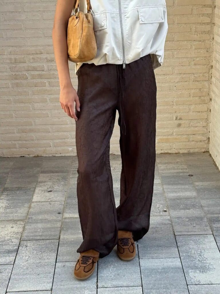 Cinematic shot of cranberry suede sneakers styled with wide-leg pants and a matching suede handbag.