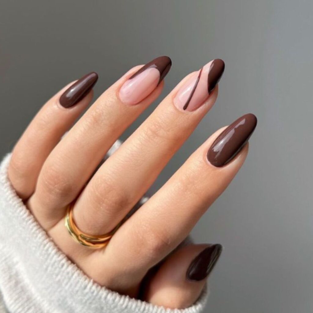Espresso manicure accented with thin metallic gold lines and shimmer details for a luxe touch.