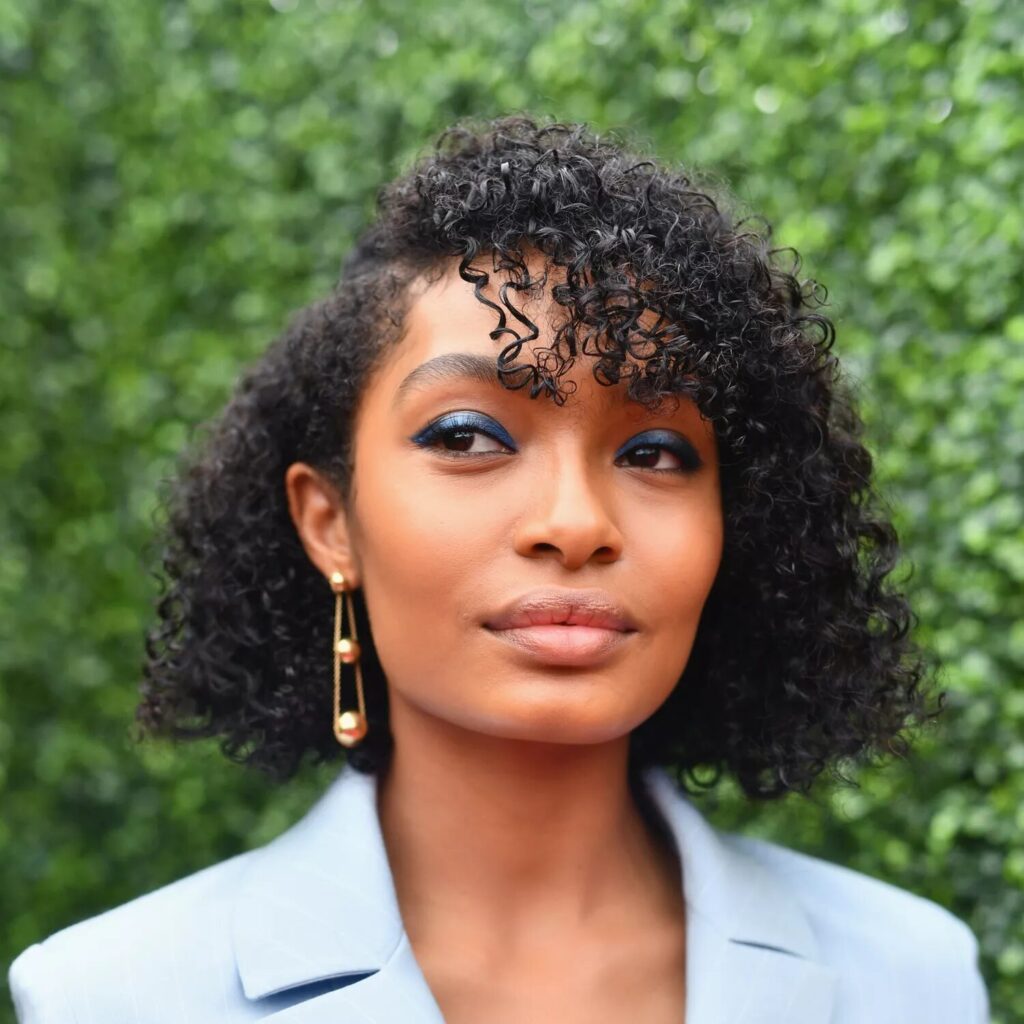 Yara Shahidi with jaw length curly bob hairstyle styled with fringe and soft curls