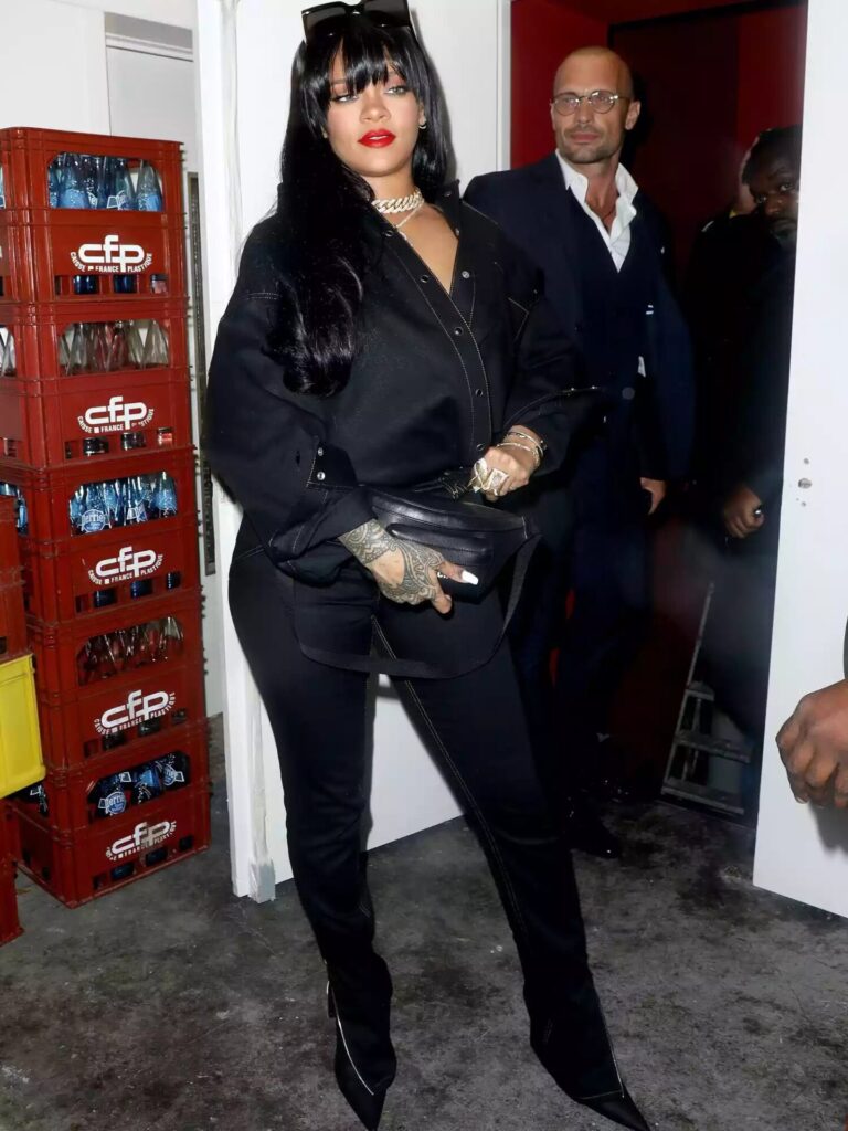 Rihanna in black denim jacket and jeans styled with a leather belt bag and black accessories for an after-dark Canadian tuxedo look.