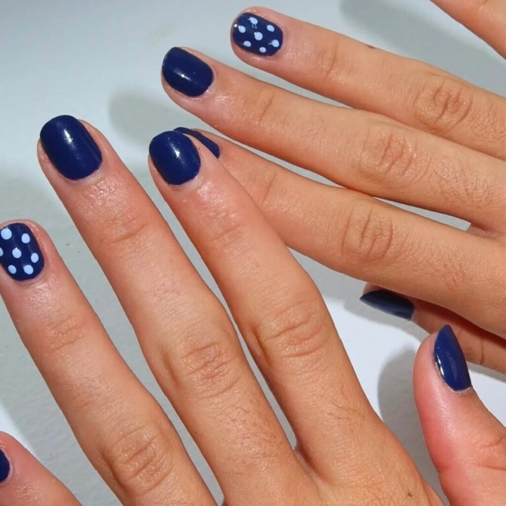 Short navy nails with playful white polka dot manicure design for October