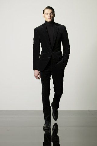 man in dark velvet blazer with turtleneck and black boots in formal setting