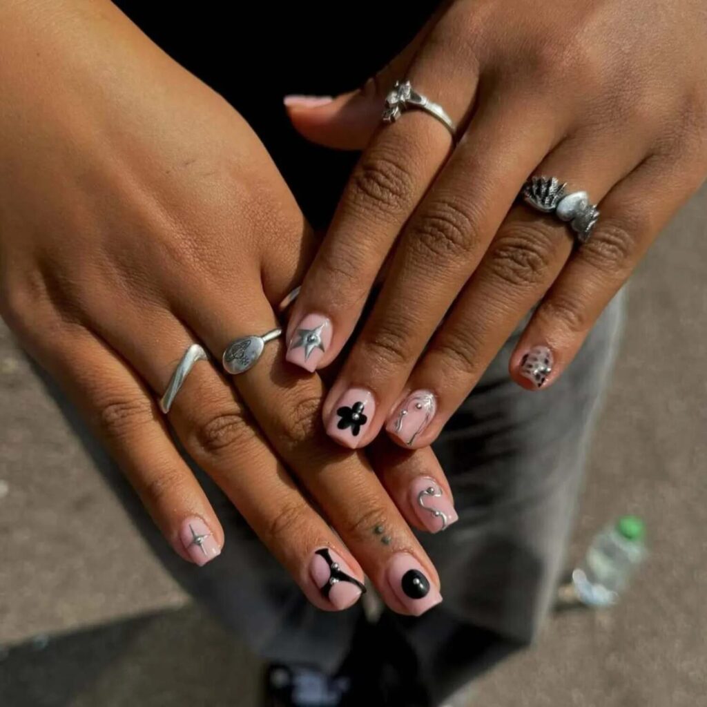 Short nails with neutral pink backdrop featuring edgy black and chrome accent nail art