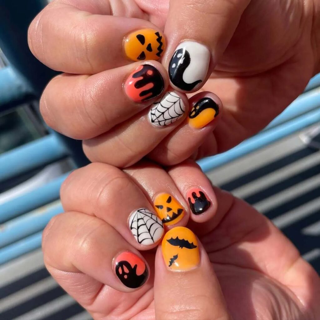 Short nails with Halloween nail art featuring pumpkins spider webs ghosts and bats