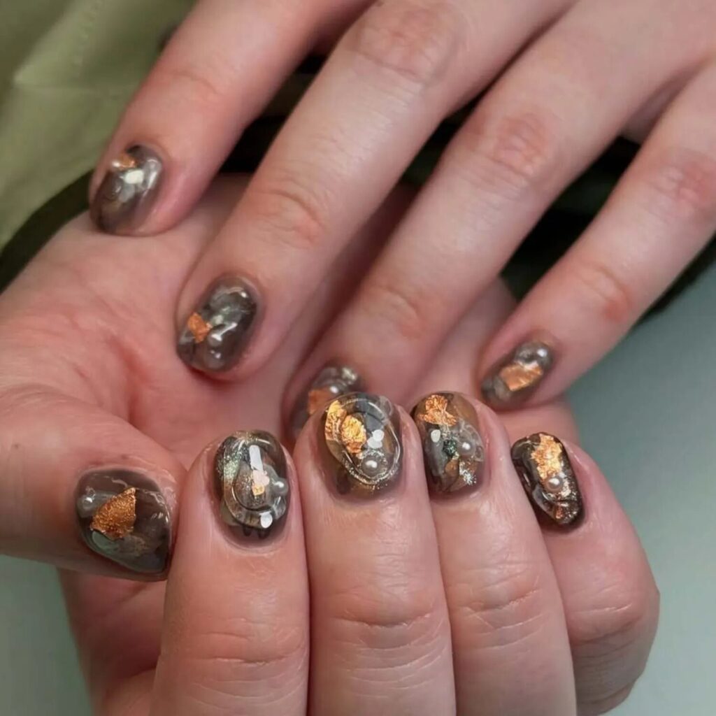 Short nails with earthy abstract manicure in moss tones gold foil accents and glossy finish