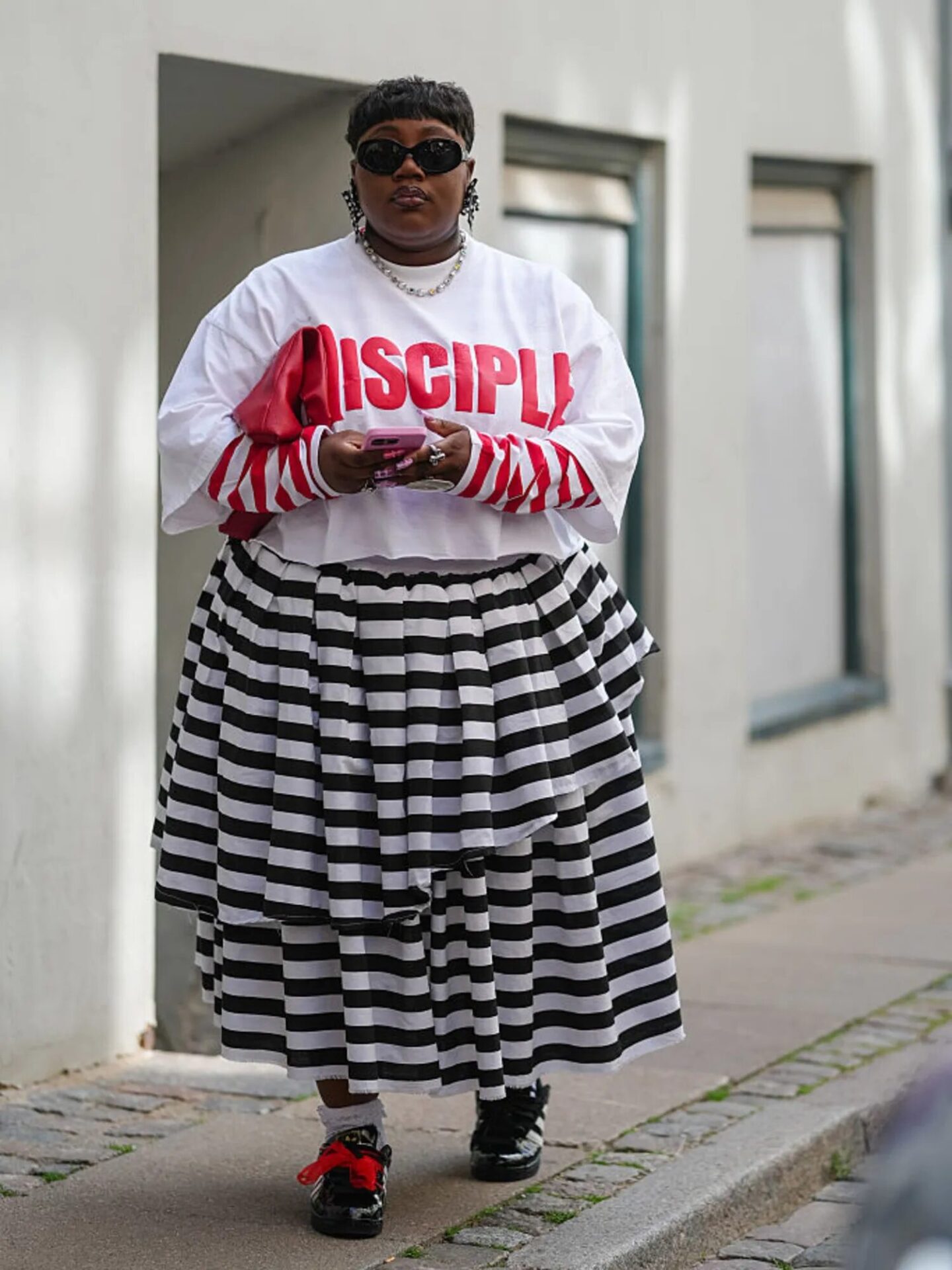 Bold outfit with mixed prints, striped skirt, and sneakers for a statement look.