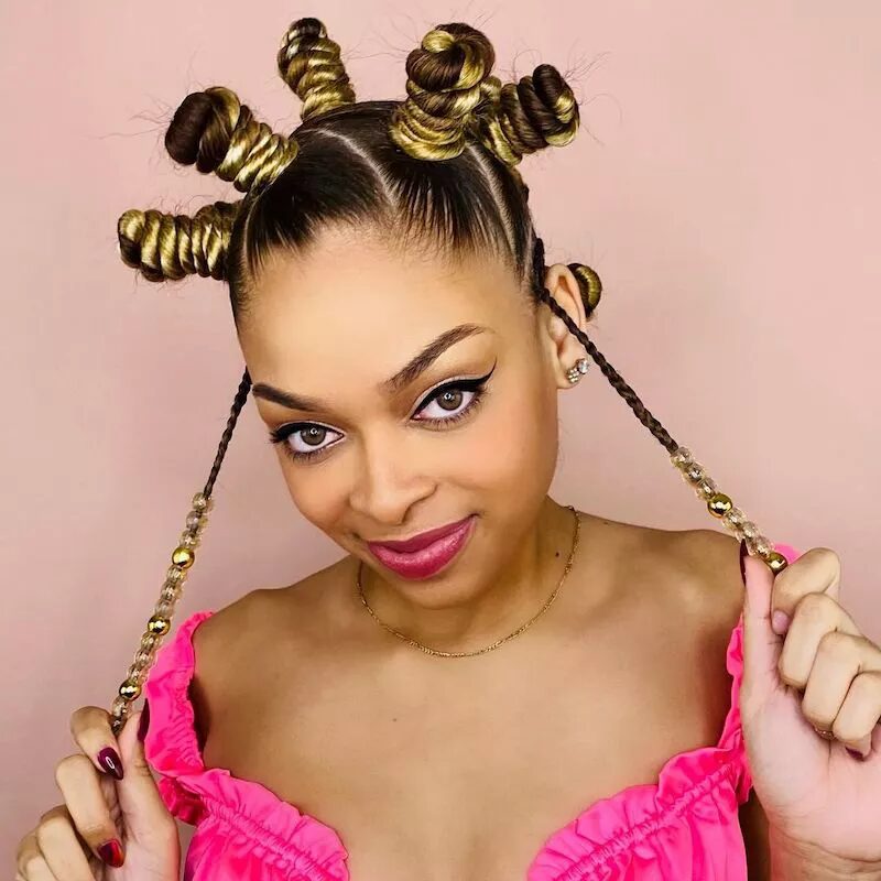 Bantu knot hairstyle with blonde highlights and face framing beaded braids under fall light