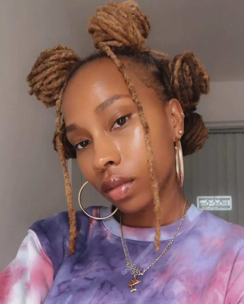 Model with blonde locs styled into twisted Bantu knots with two loose front locs