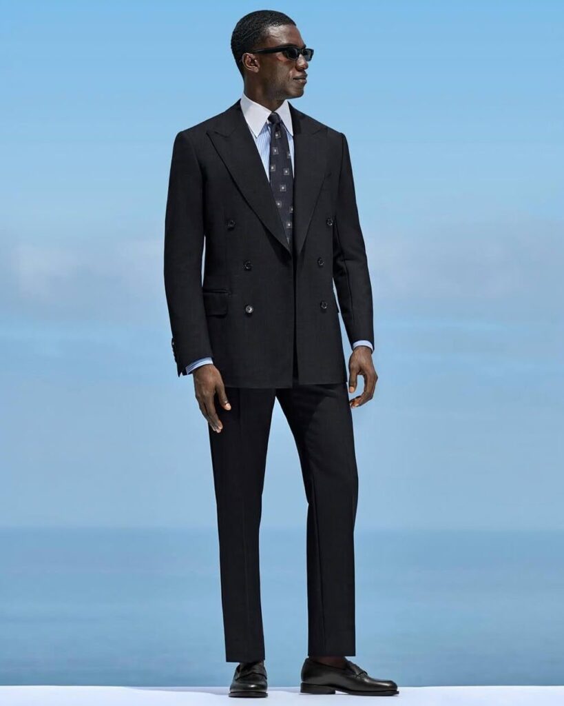 Businessman adjusting Suitsupply Havana navy suit jacket with crisp white shirt, reflecting affordable luxury tailoring.