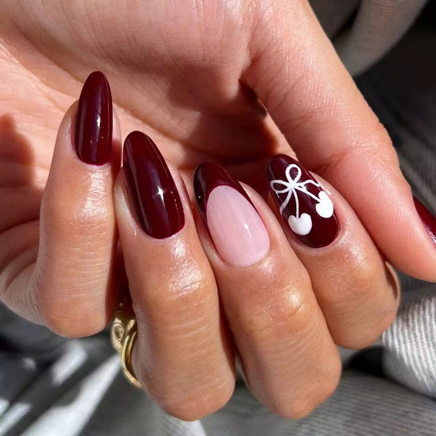 Burgundy nails with cherry nail art and French tips for a playful, youthful fall manicure look.