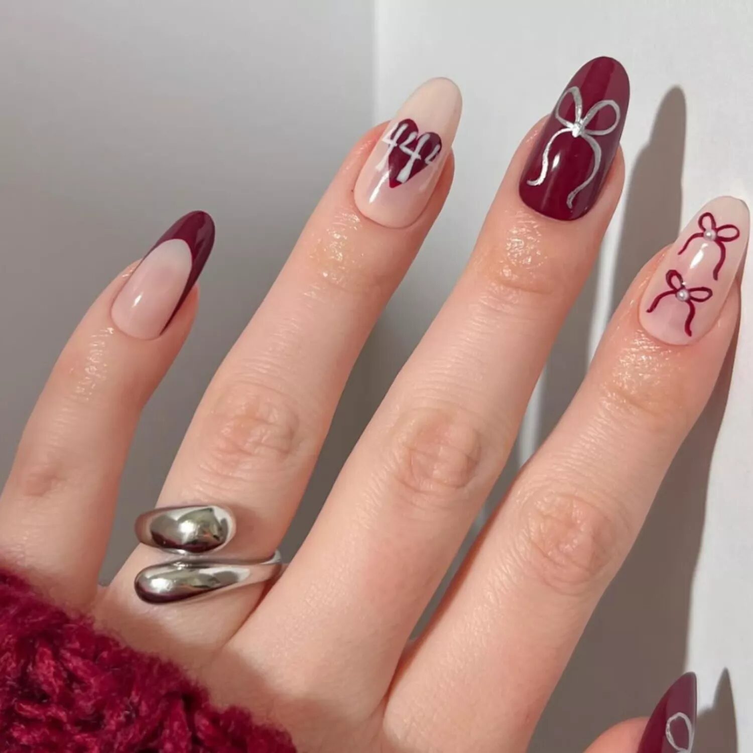 Negative space manicure with abstract burgundy chrome waves for a minimalist artistic nail design.