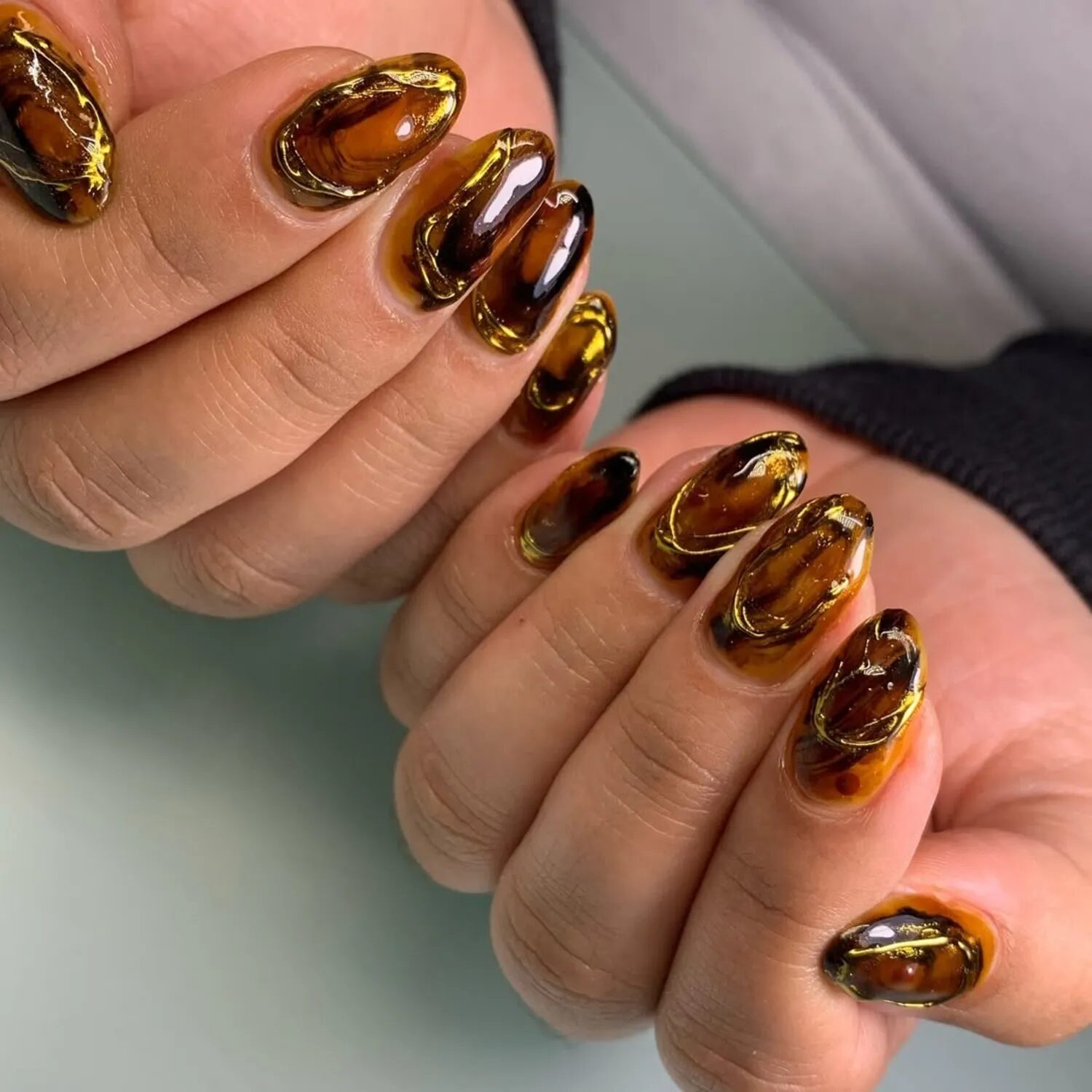 Glossy tortoiseshell nails with raised gold chrome accents