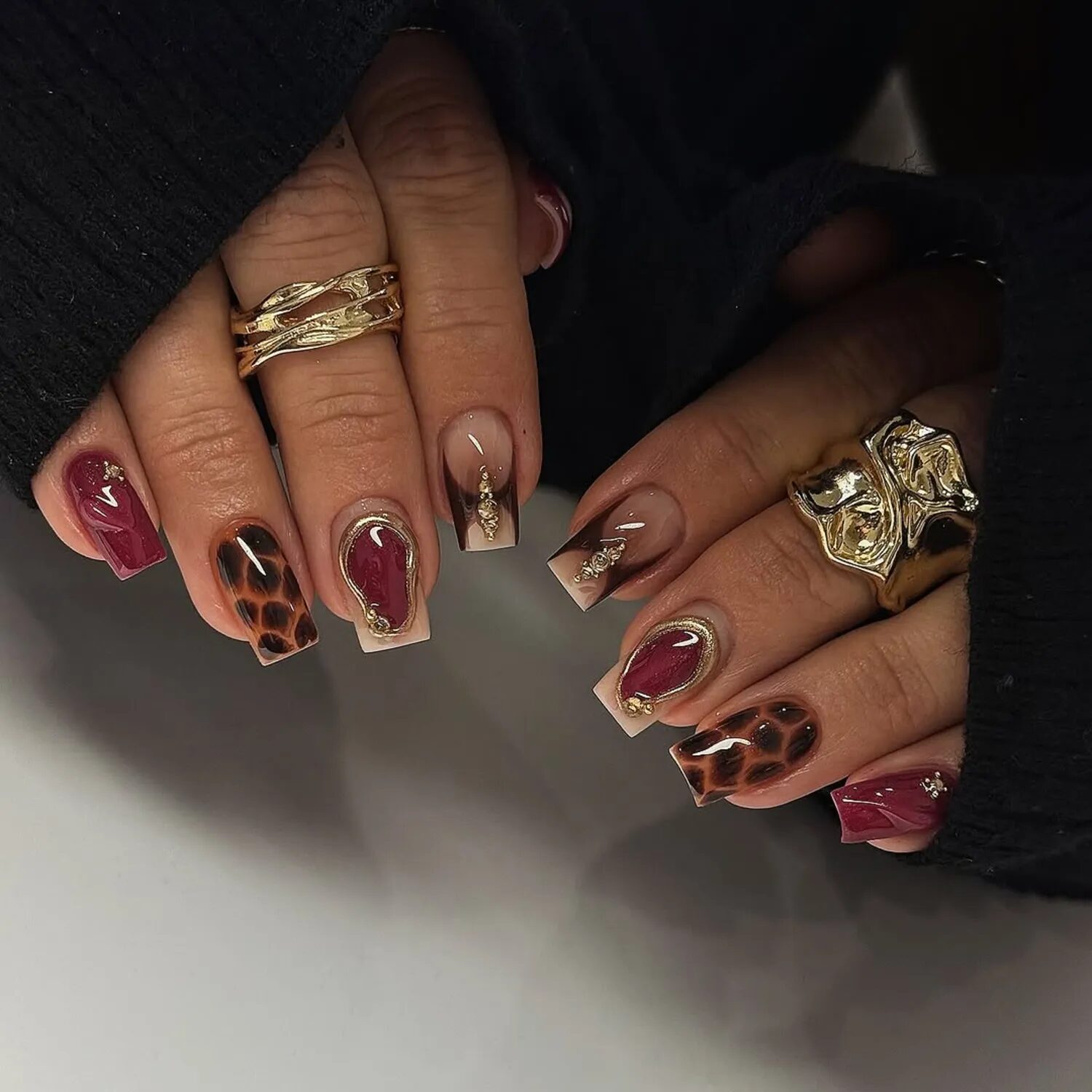 Mismatched autumn chrome nails in terracotta, sage, and burgundy tones with gold accents