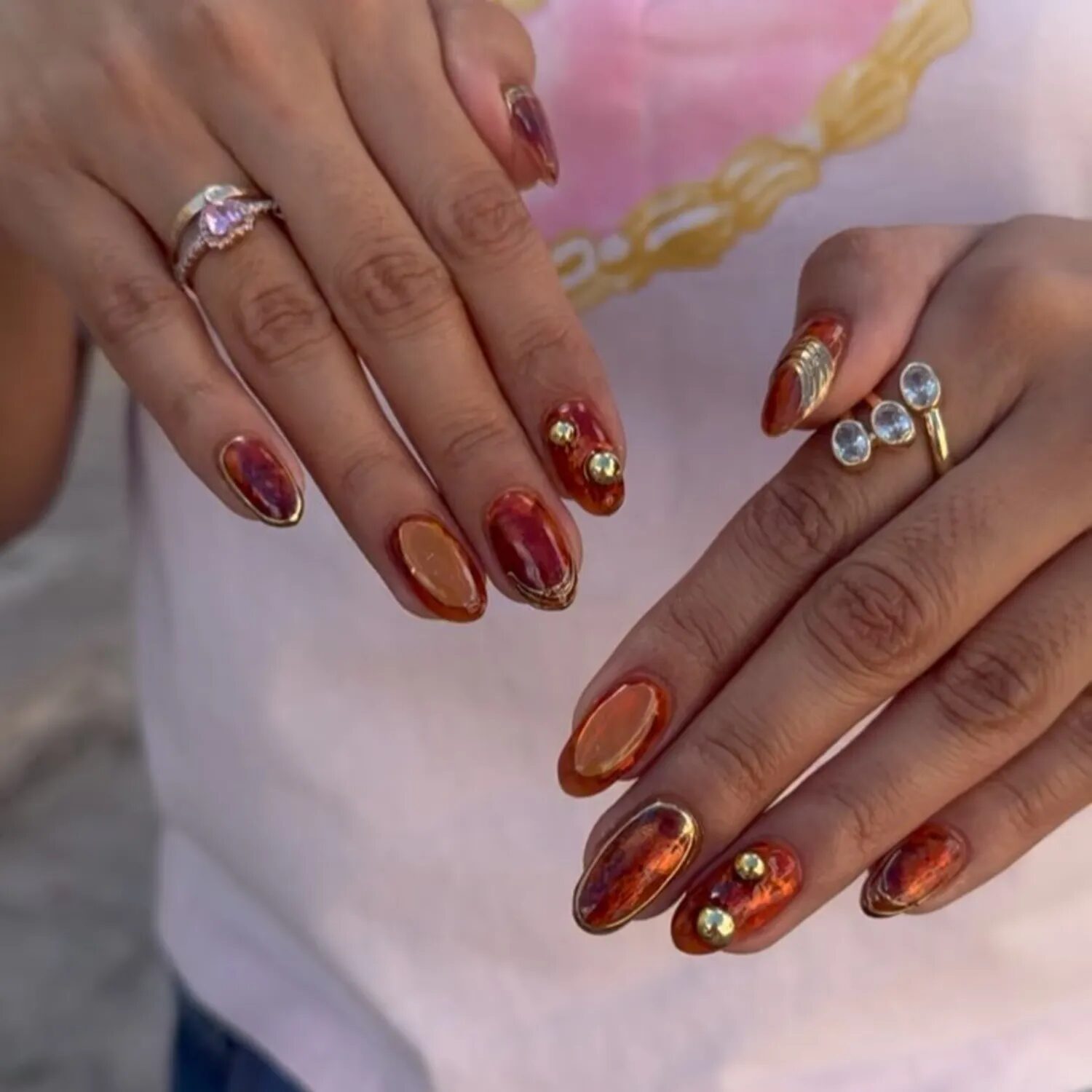 Reflective burnt orange chrome nails shining in sunlight
