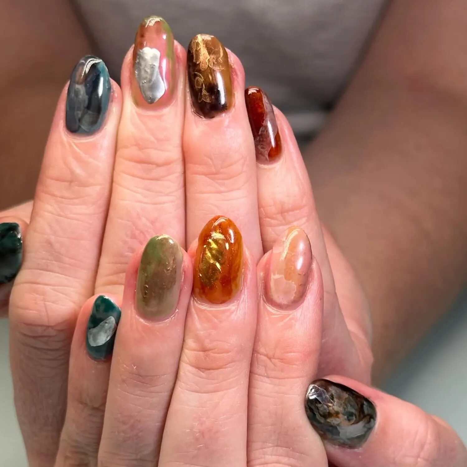 Multicolored chrome Skittle manicure with earthy fall hues and marble accents)