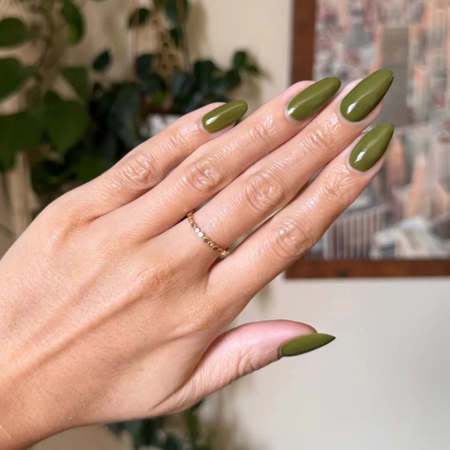 Long stiletto nails in deep olive green shade with a modern minimalist look