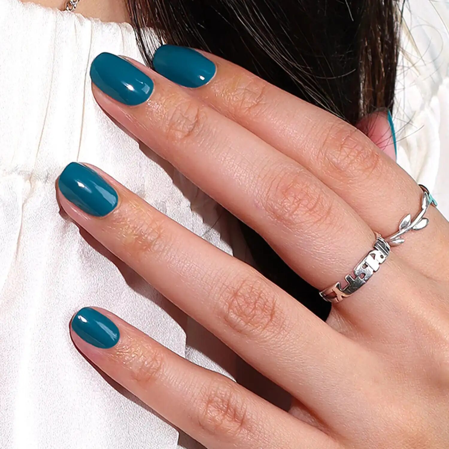 Nails painted in jewel-toned teal color reflecting blue-green autumn hues