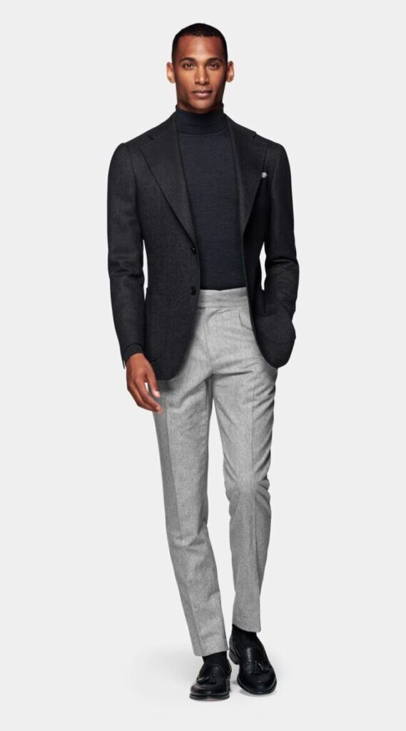 man wearing carbon trench and black turtleneck with dark trousers