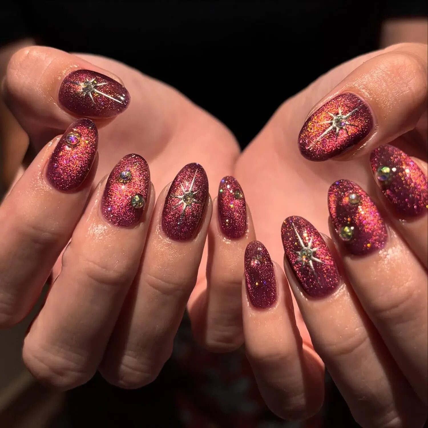 Bordeaux red velvet nails with gold chrome accents and celestial-inspired moody shimmer.