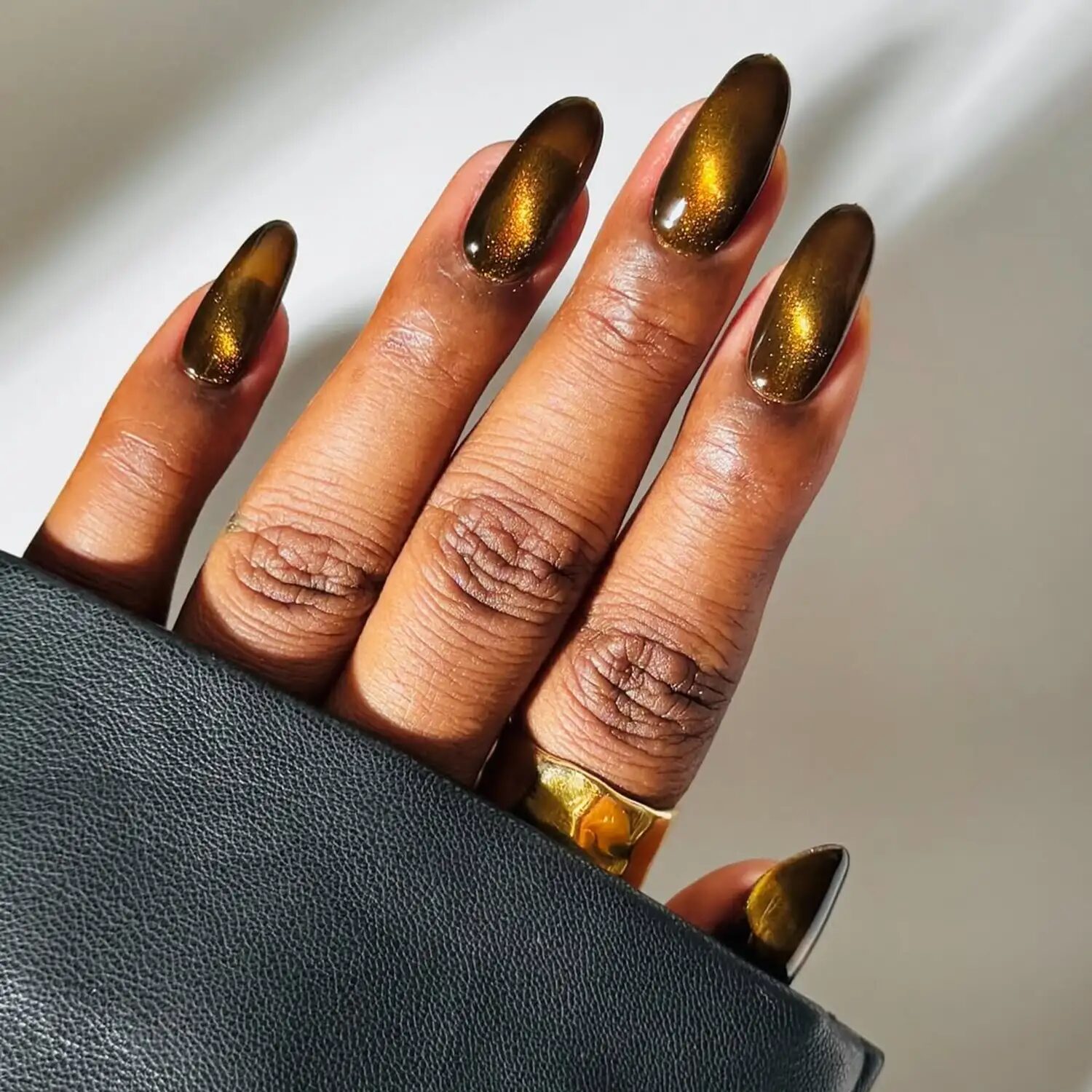 Golden velvet cat-eye manicure with gemstone-inspired shimmer and candlelit reflection.