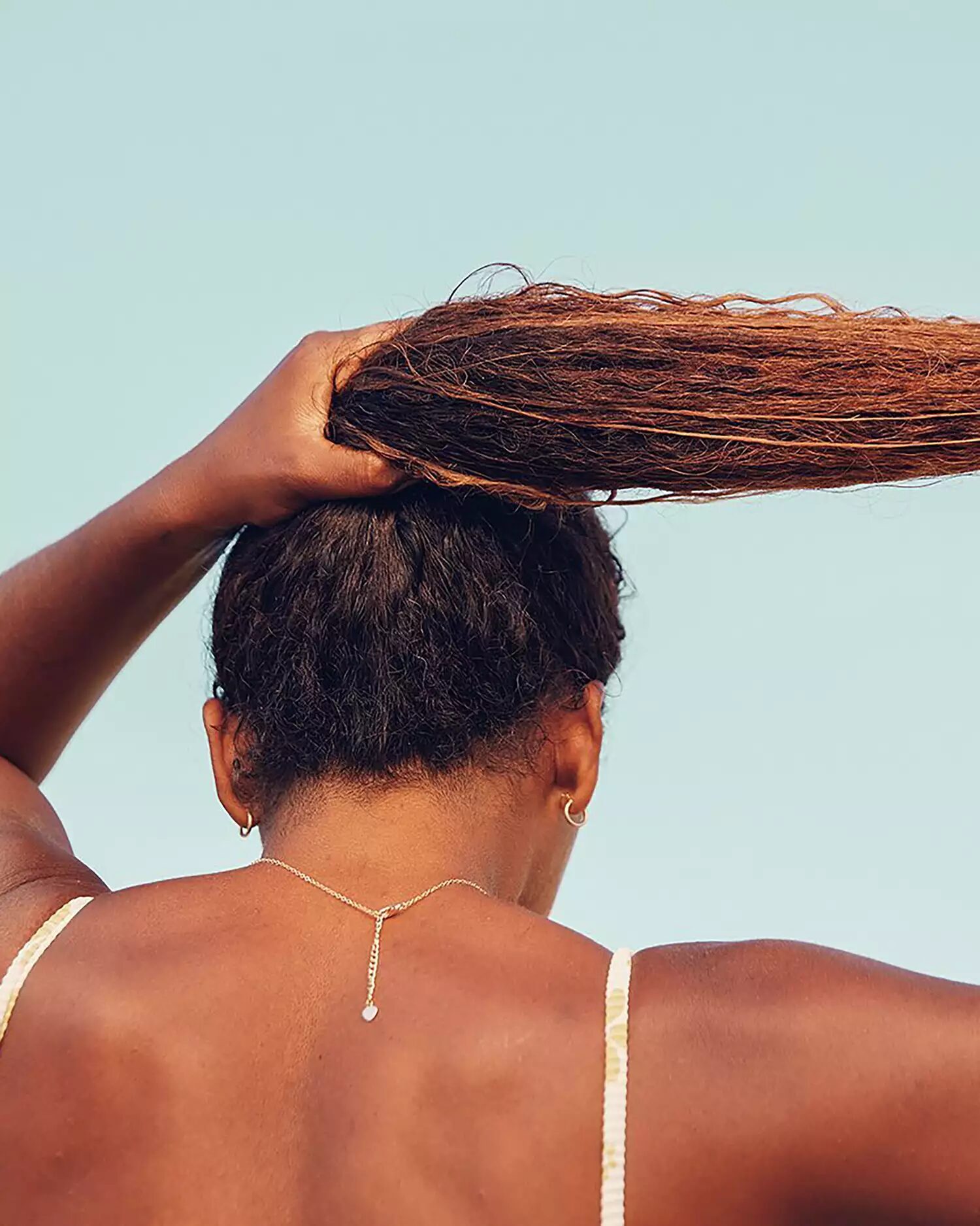 Lightweight scalp sunscreen spray applied outdoors to protect hair and prevent sun damage.