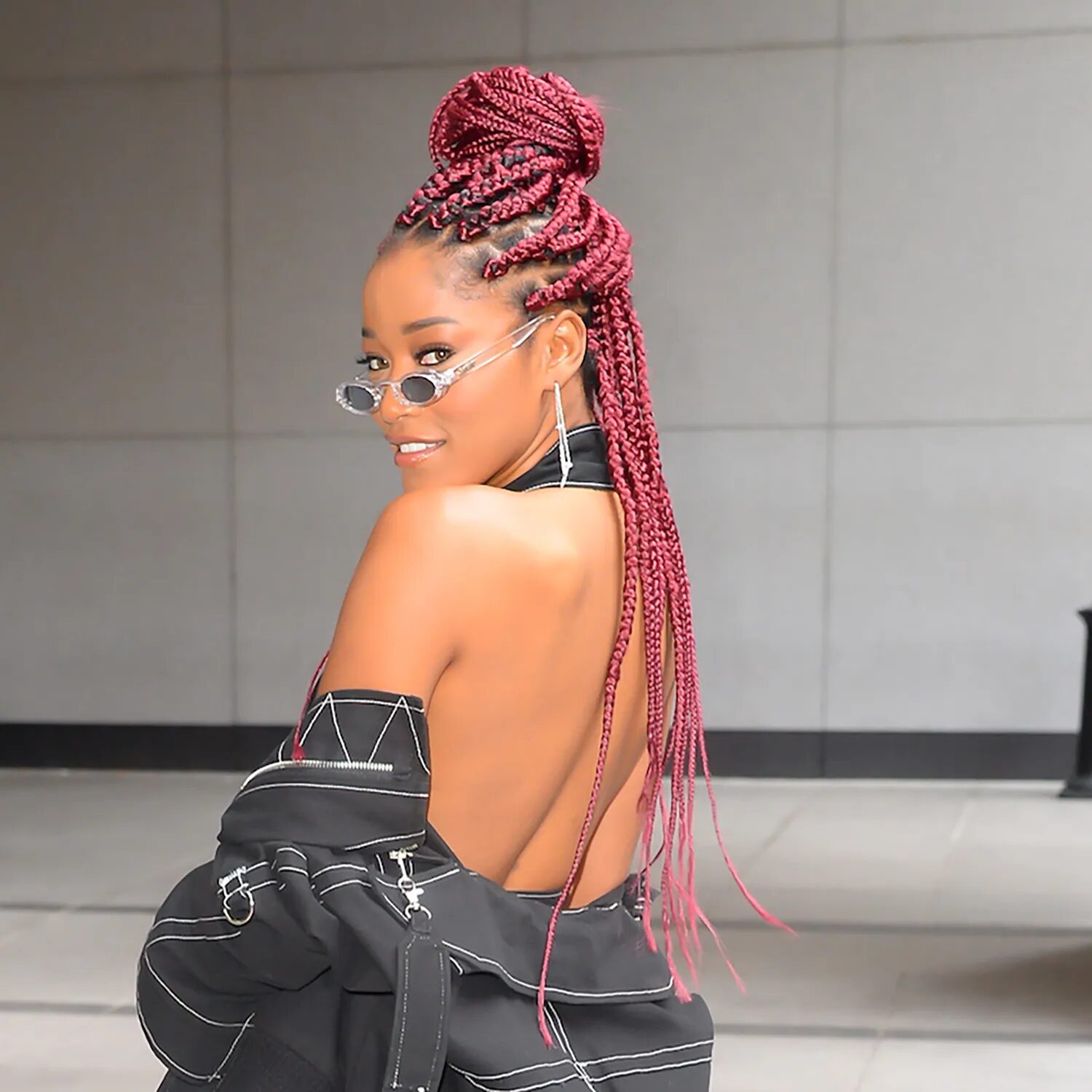 Model with burgundy box braids posing outdoors in autumn light, highlighting deep red undertones.