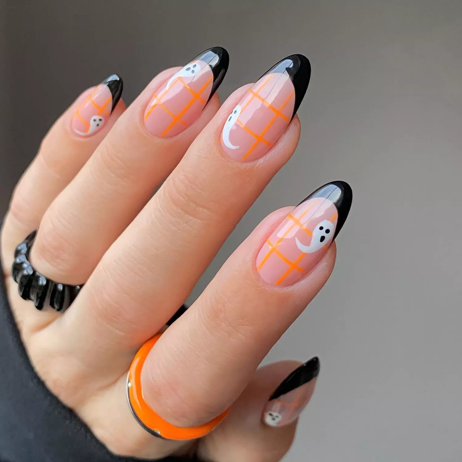 Black French tips with orange grid lines and white ghost nail art for playful spooky manicure.