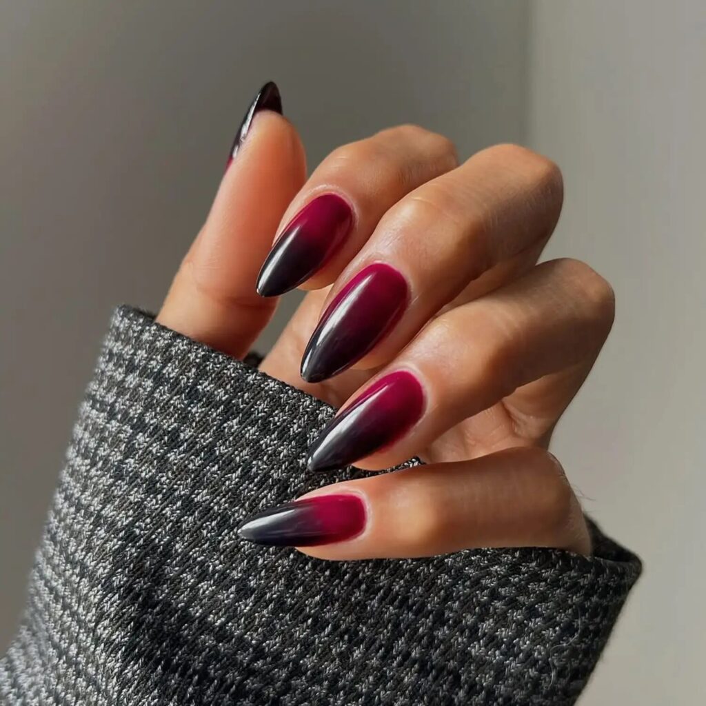 Almond-shaped nails featuring a smooth black-to-berry ombré fade with glossy finish
