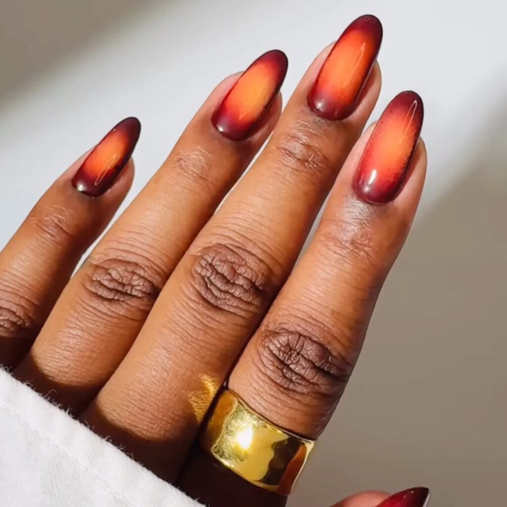 Warm orange ombré nails with golden glow capturing cozy fall energy