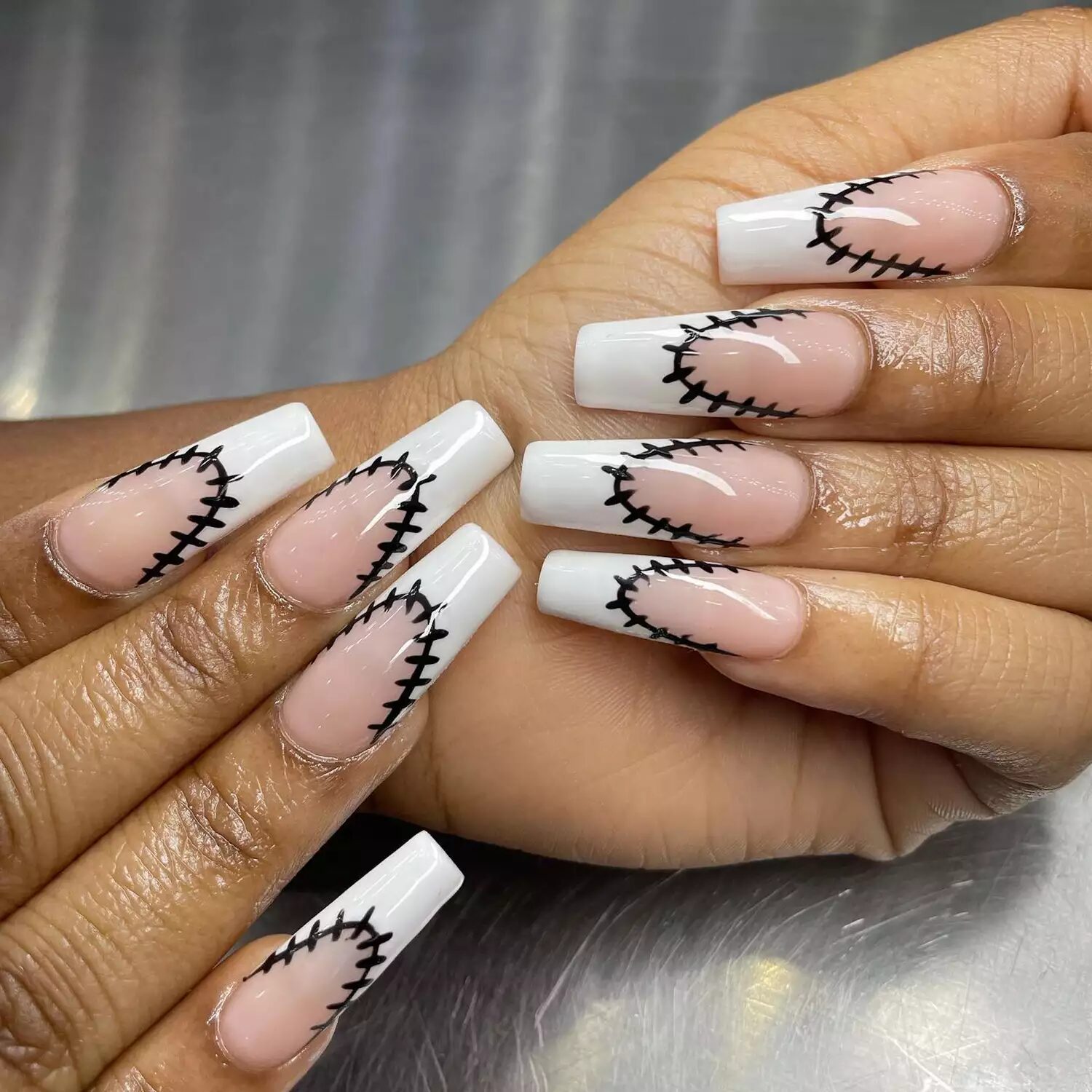 White French tips with black stitches inspired by Frankenstein Halloween manicure design.