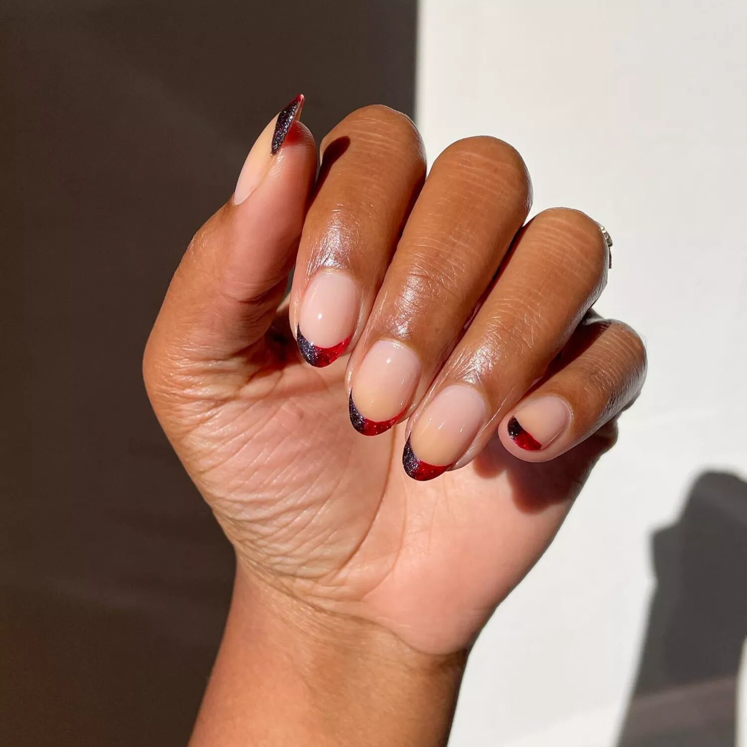 Short nails with red and black ombre French tips featuring glittery vampire-inspired gradient.