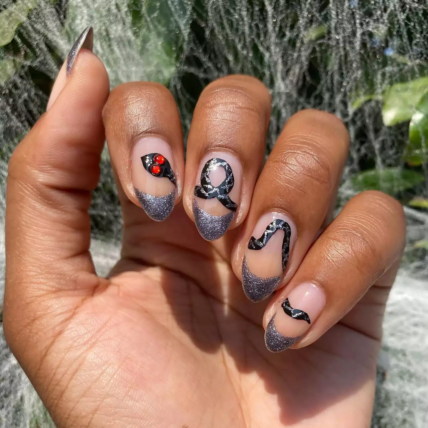 Gray sparkly French tips with snake design and red eyes for bold reptile Halloween manicure.