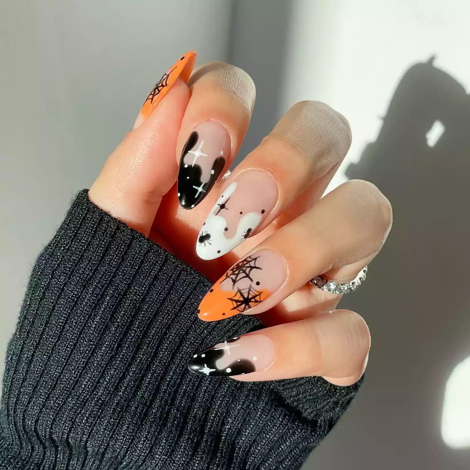 Halloween French manicure with orange, black, and white tips, spider webs, and star accents.