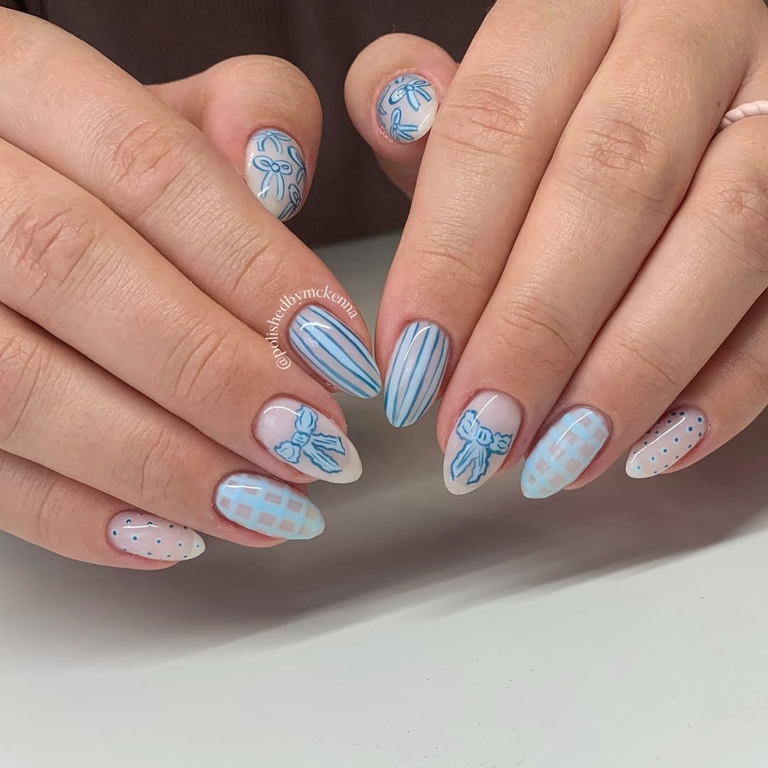 Baby blue nails with hand-drawn ribbons, bows, and nursery stripes