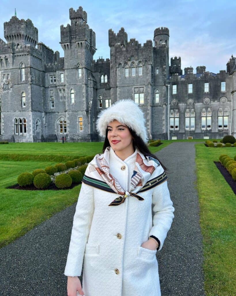 Woman in a tailored coat and scarf, presenting a classic look with a heritage feel.