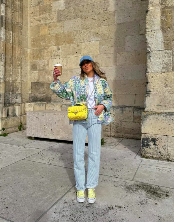 A patterned jacket with light denim and a bright accessory.