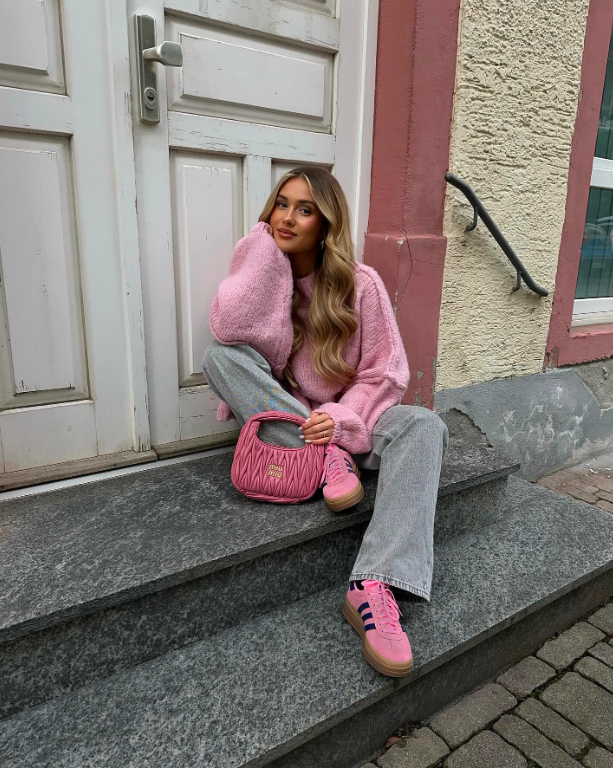 An oversized pink sweater paired with denim and sneakers.