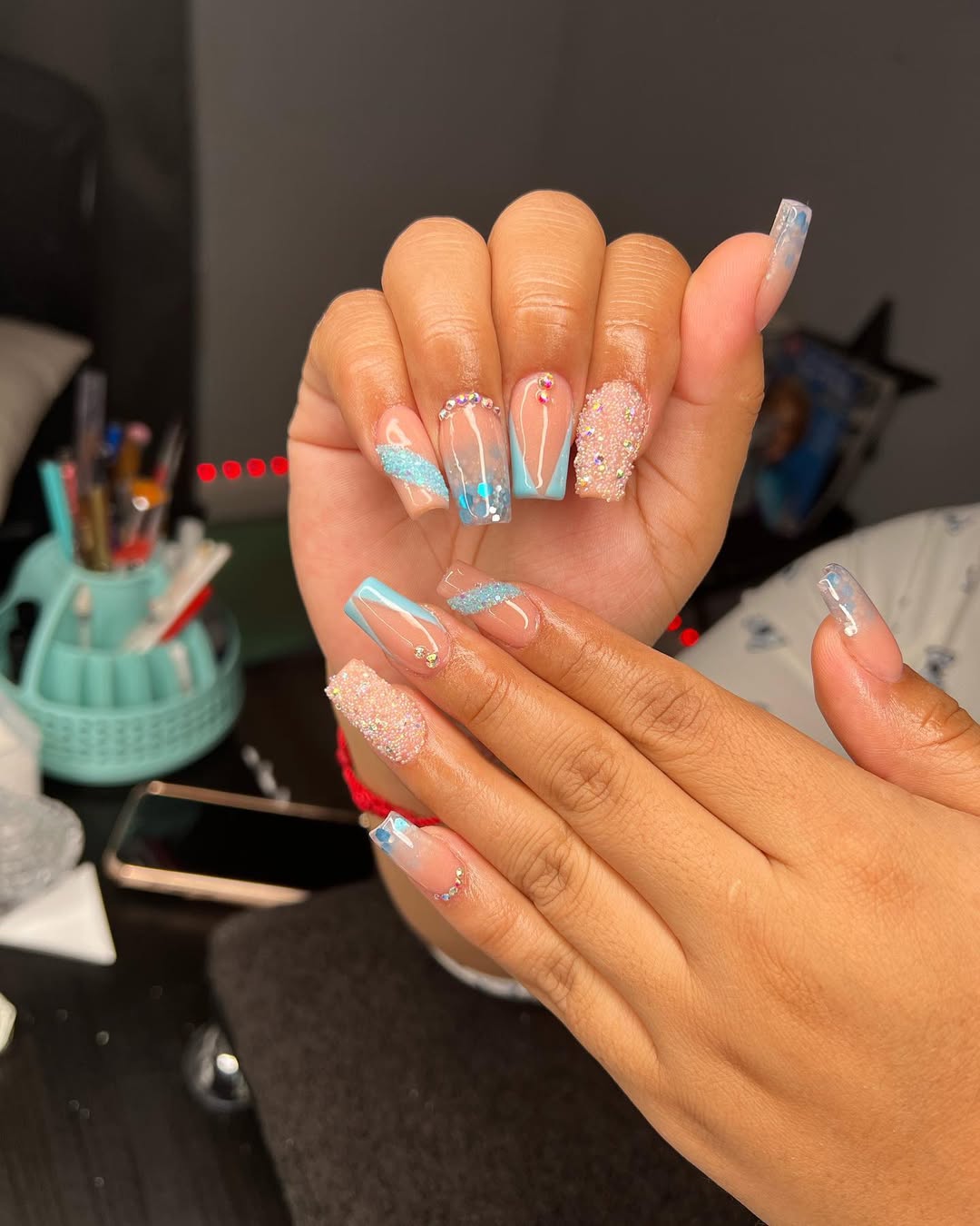 Glossy blue nails with glitter, crystals, and textured accents