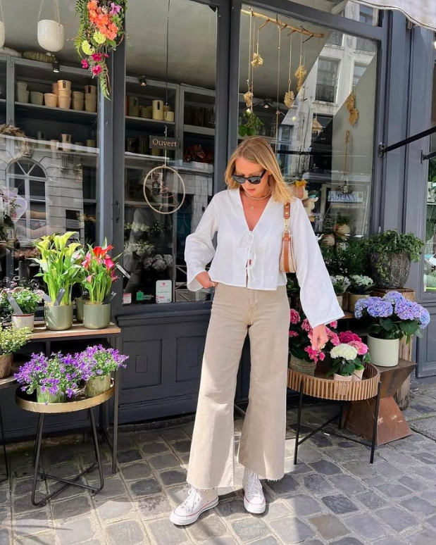 An airy white blouse with neutral wide-leg pants and sneakers.