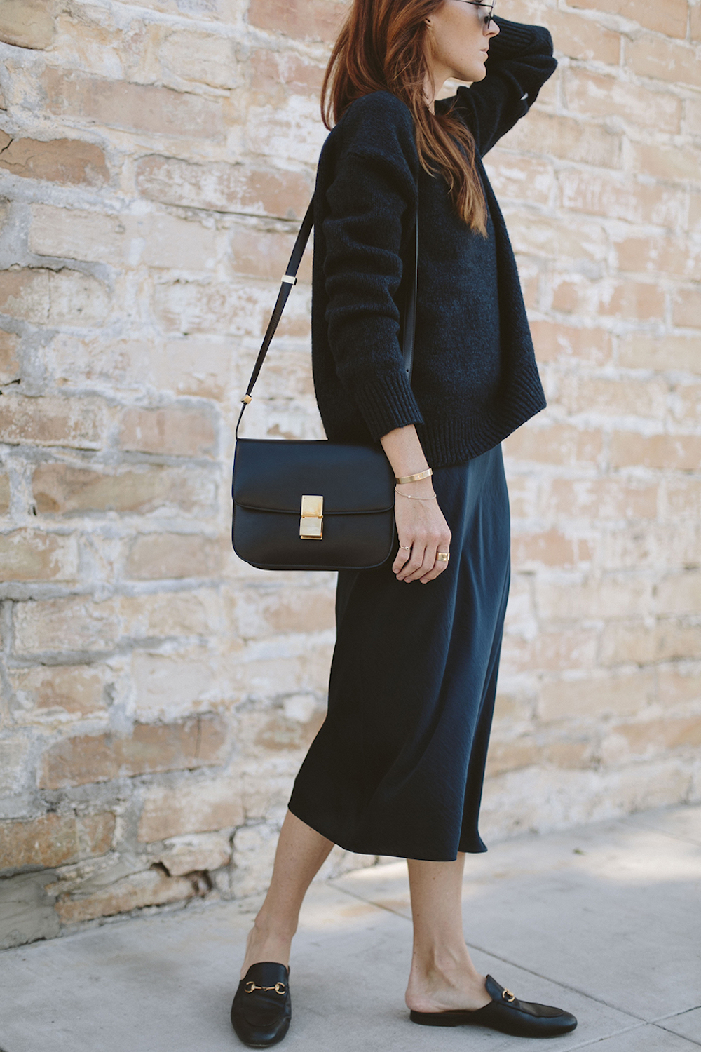 image of a woman in a black sweater over a black silk slip dress with a black purse and black shoes
