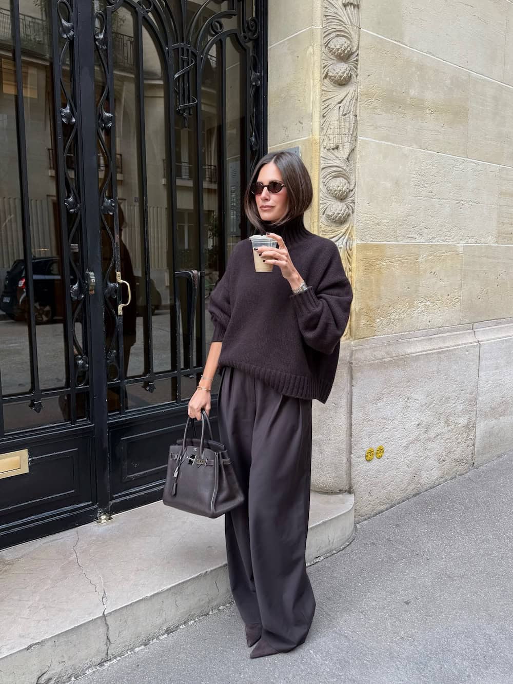 a woman wearing wide leg brown trousers, a brown turtleneck sweater, and brown heels