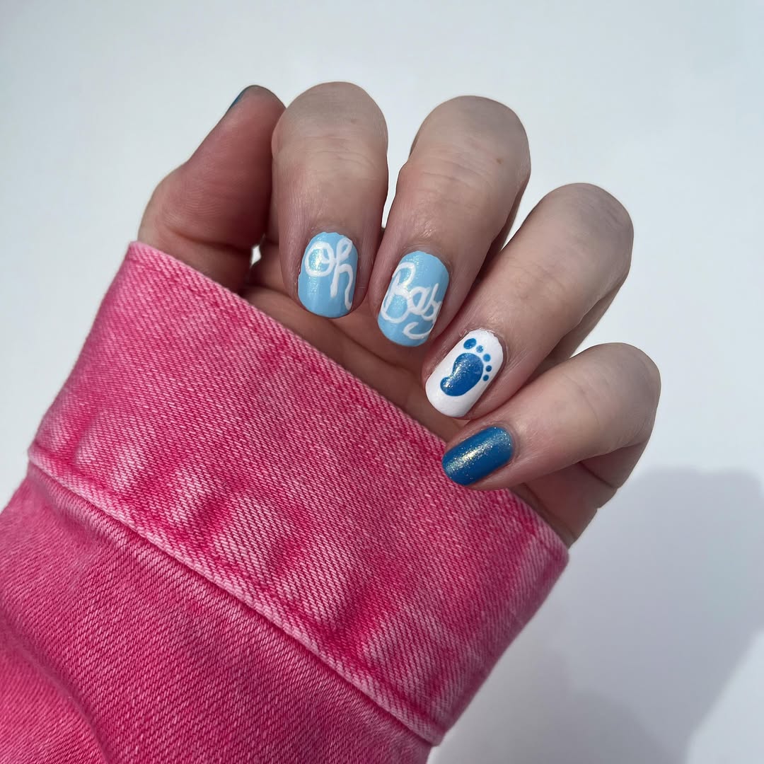 Soft blue nails with 'Oh Baby' lettering and a single footprint