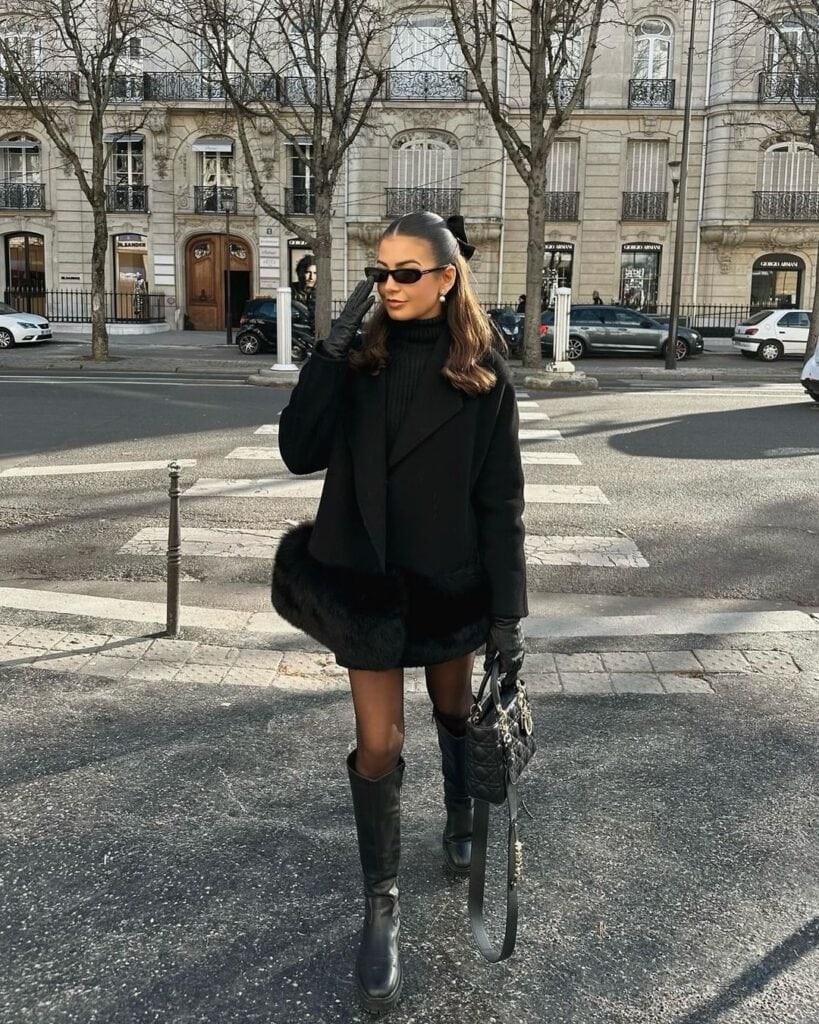 Woman in an all-black outfit with rich textures and sharp accessories, embodying Parisian chic.