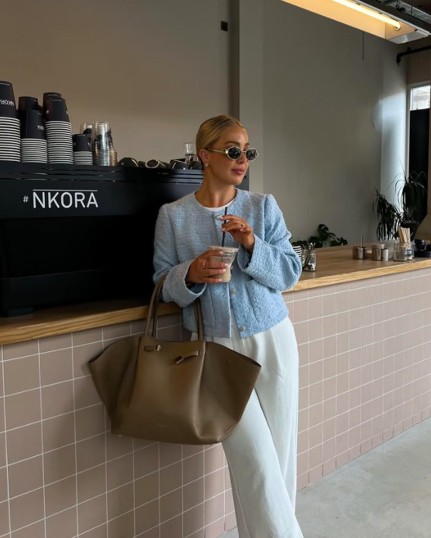 A woman in a light blue jacket and cream trousers for a stylish coffee break.