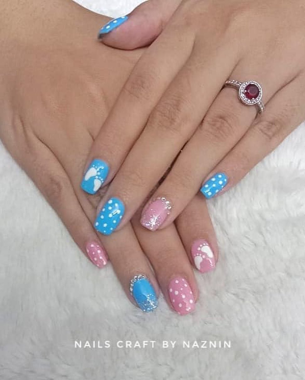 Pink and blue nails with polka dots, footprints, and rhinestones