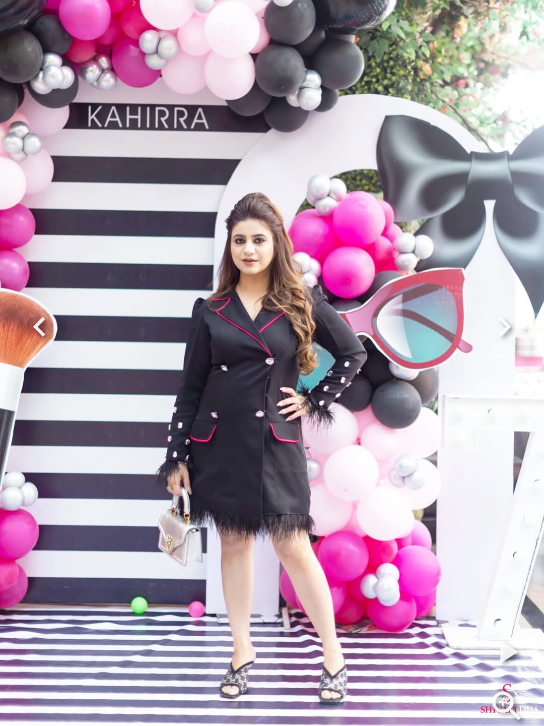 A black blazer dress with feathered hem and pink piping.